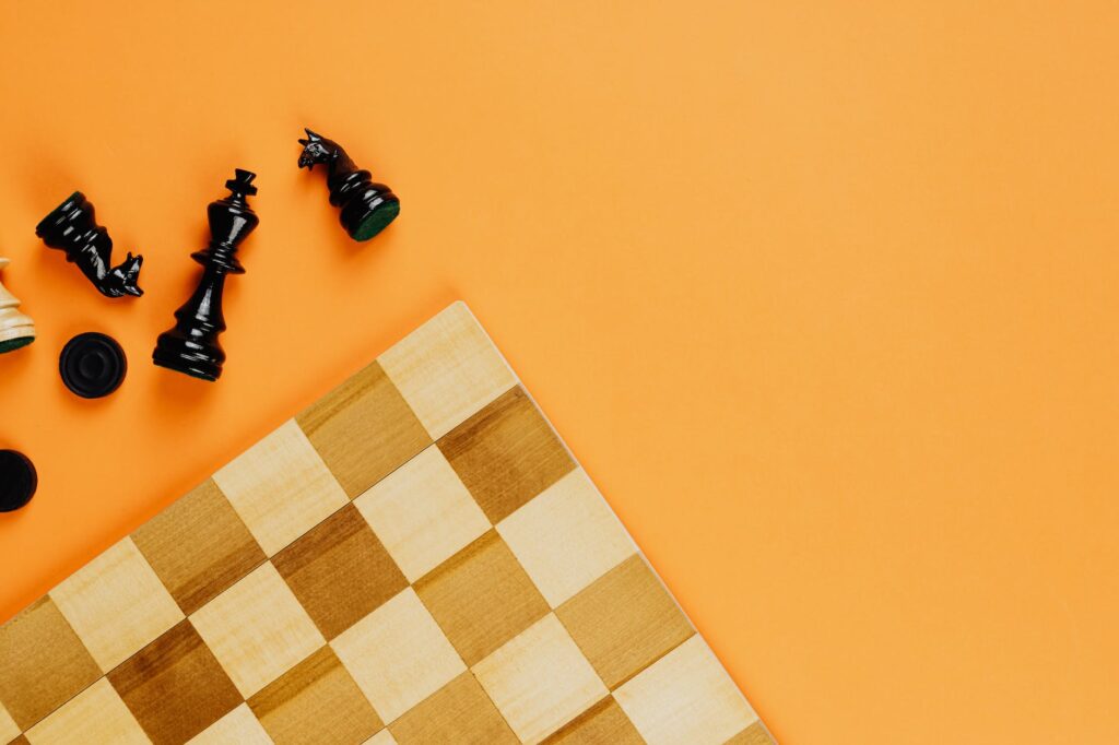 chess board and black chess pieces beside on yellow background