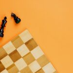 chess board and black chess pieces beside on yellow background